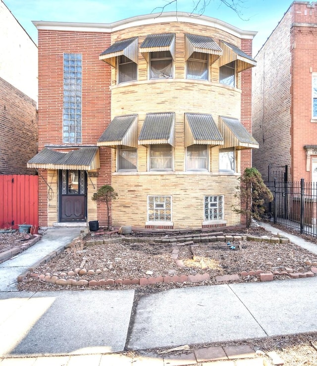 view of front of home with fence, brick siding, and stone siding