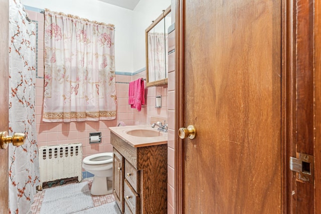 full bathroom featuring toilet, radiator, tile walls, wainscoting, and vanity