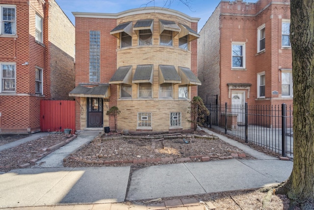 townhome / multi-family property with fence and brick siding