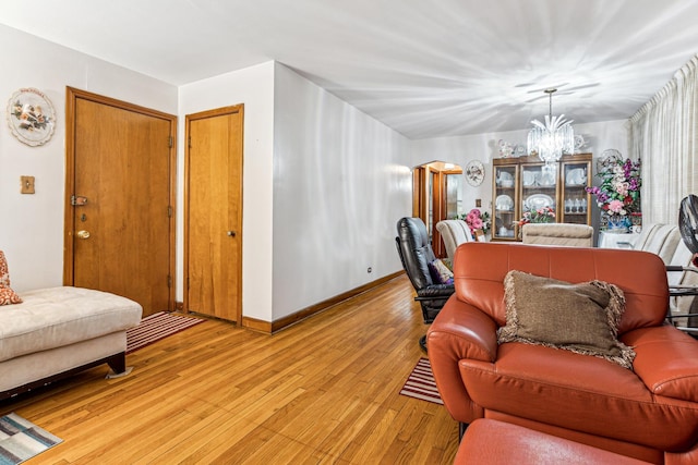 living room with light wood-style flooring, baseboards, and an inviting chandelier