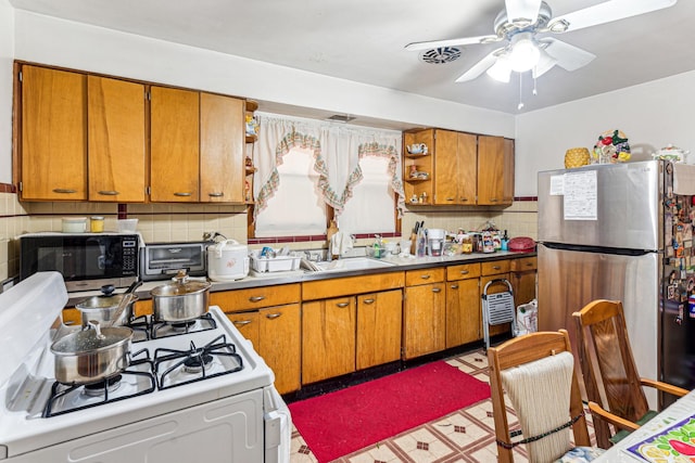 kitchen featuring a sink, brown cabinets, stainless steel appliances, and open shelves