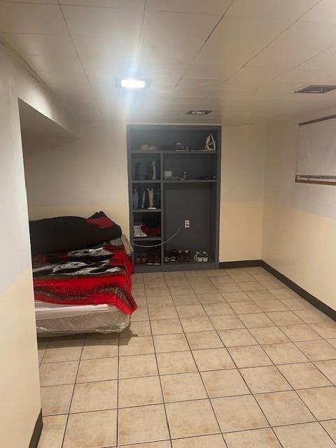 bedroom featuring light tile patterned floors, visible vents, and baseboards