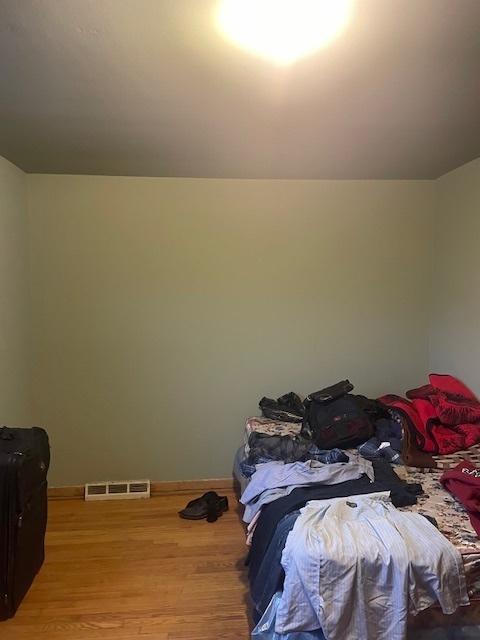 bedroom featuring lofted ceiling, light wood-type flooring, visible vents, and baseboards