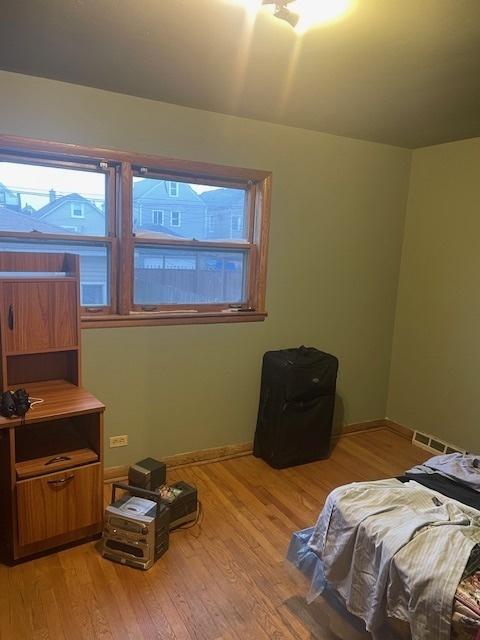 bedroom featuring baseboards, visible vents, and light wood finished floors