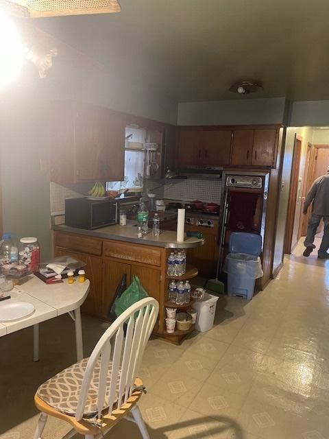 kitchen featuring black microwave, light countertops, and brown cabinets