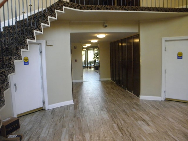 interior space featuring a high ceiling, stairway, wood finished floors, and baseboards