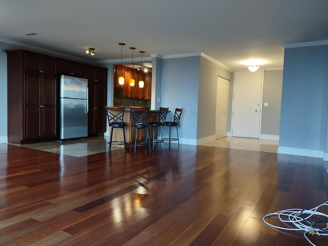 kitchen with light wood-type flooring, a breakfast bar, backsplash, and freestanding refrigerator