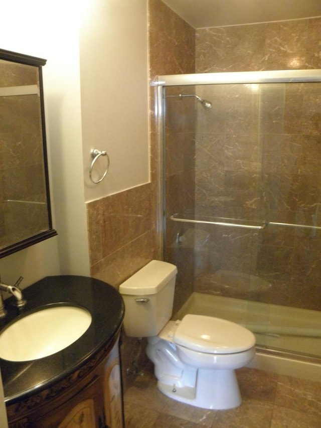 full bath featuring toilet, a shower stall, tile walls, and vanity