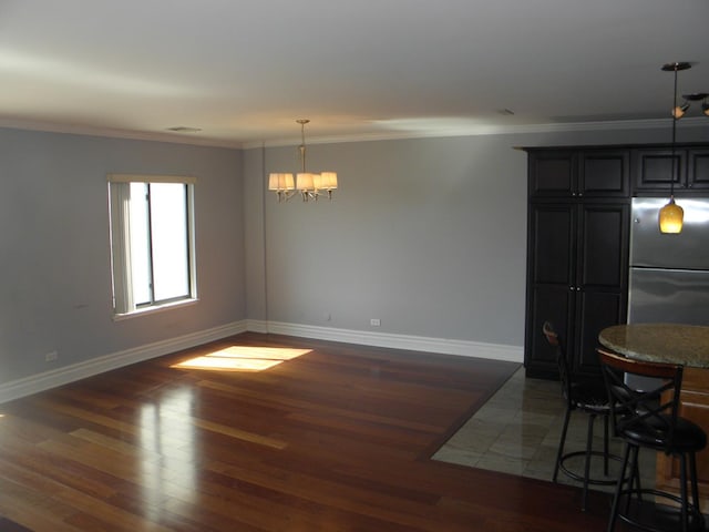 dining room featuring ornamental molding, a chandelier, baseboards, and wood finished floors