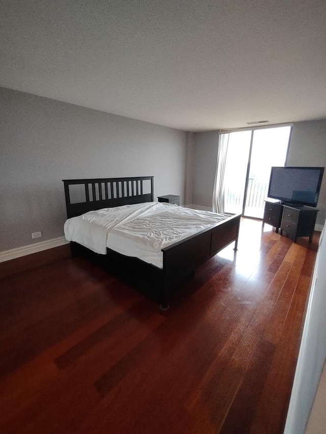 unfurnished bedroom featuring expansive windows, wood finished floors, and baseboards