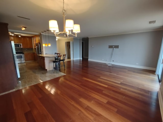 kitchen featuring a notable chandelier, stainless steel appliances, light countertops, wood finished floors, and a kitchen breakfast bar