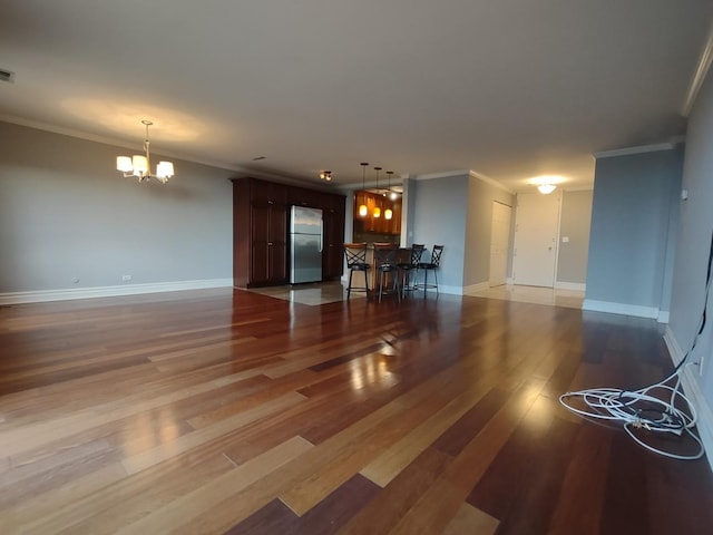 unfurnished living room with ornamental molding, light wood finished floors, and an inviting chandelier