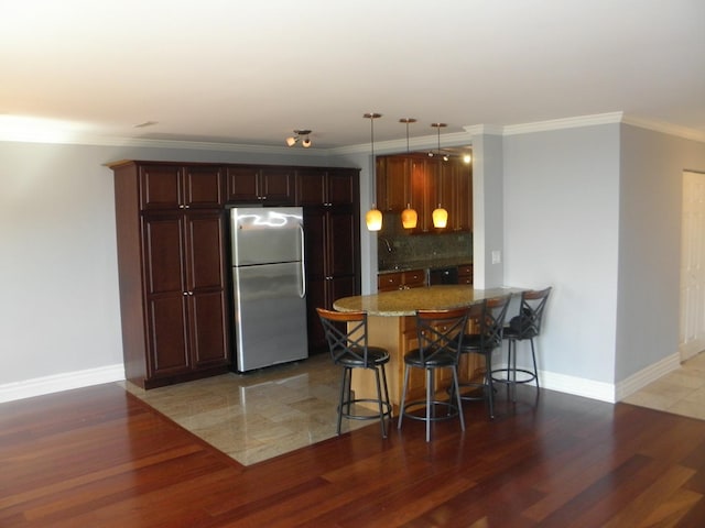 kitchen featuring light wood-style flooring, a breakfast bar, freestanding refrigerator, and tasteful backsplash