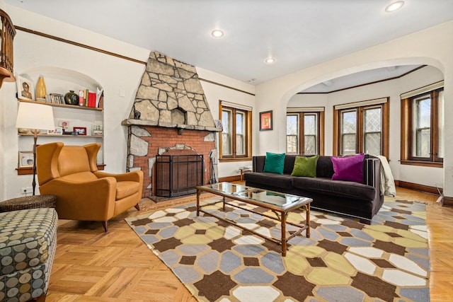 living room featuring arched walkways, recessed lighting, a fireplace, and baseboards