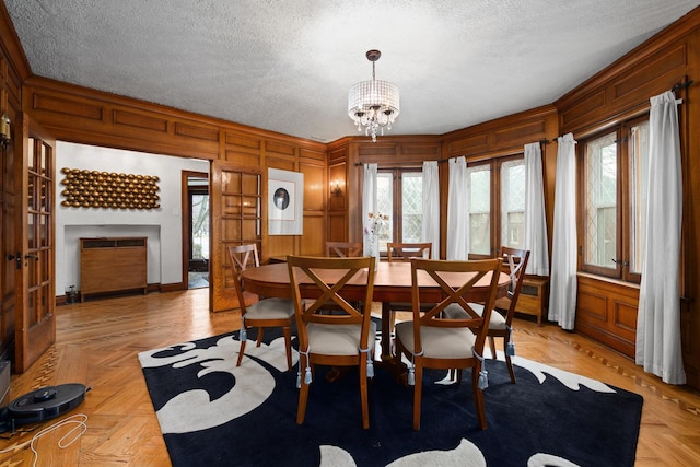 dining space featuring a wealth of natural light, a notable chandelier, a textured ceiling, and a decorative wall