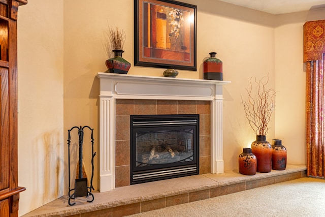 interior details with a tiled fireplace and carpet flooring