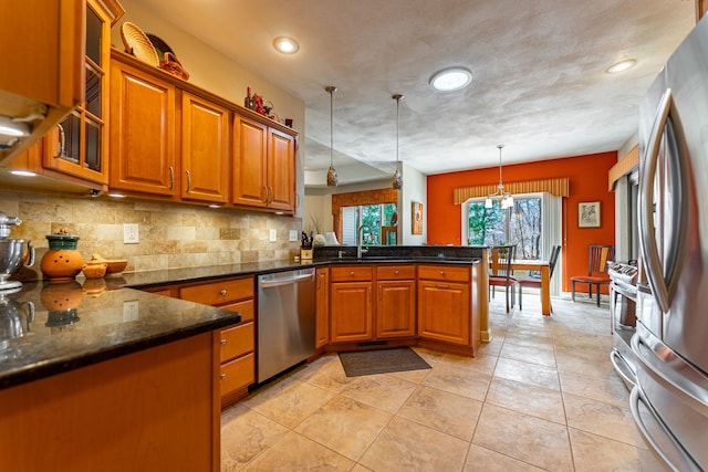 kitchen with a peninsula, brown cabinets, appliances with stainless steel finishes, and a sink