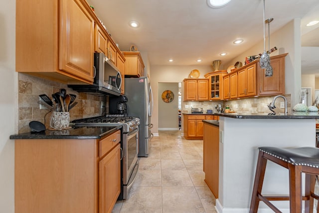 kitchen featuring glass insert cabinets, light tile patterned floors, brown cabinets, a peninsula, and stainless steel appliances