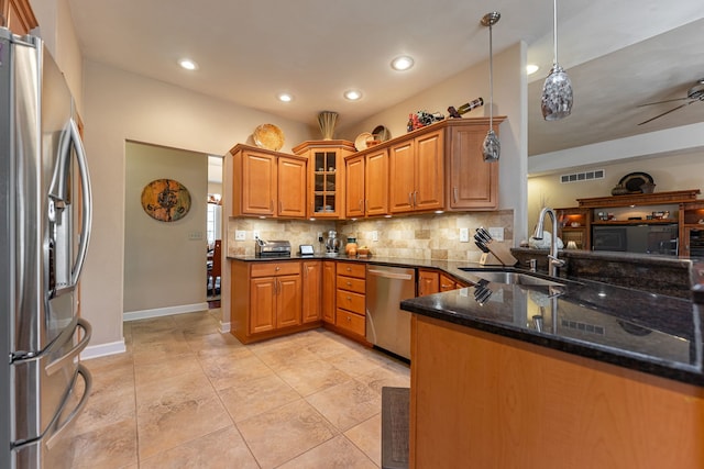 kitchen featuring tasteful backsplash, visible vents, dark stone countertops, stainless steel appliances, and a sink