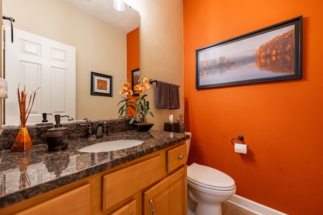 half bathroom with toilet, vanity, and baseboards