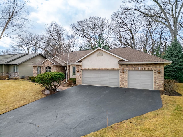 ranch-style home featuring an attached garage, stucco siding, a front lawn, aphalt driveway, and brick siding