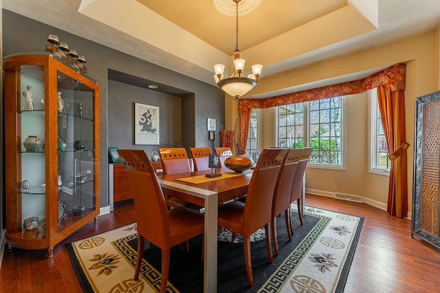 dining room with visible vents, a raised ceiling, and wood finished floors