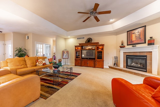 living area with visible vents, baseboards, a tiled fireplace, carpet flooring, and a raised ceiling