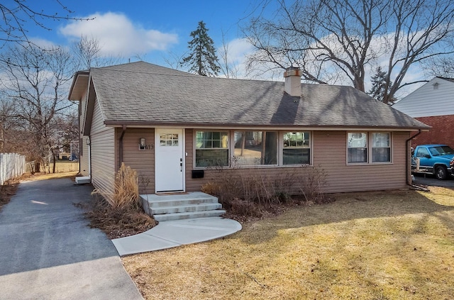 view of front of house featuring a shingled roof, a front lawn, fence, a chimney, and driveway