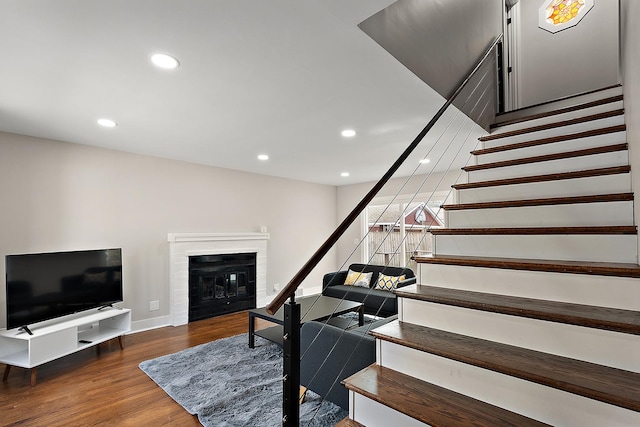 stairs with recessed lighting, a brick fireplace, baseboards, and wood finished floors