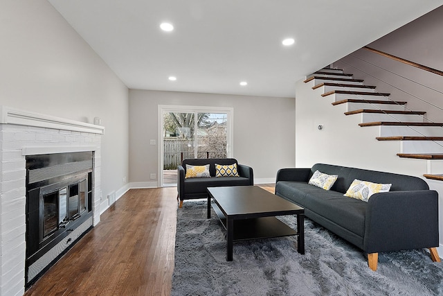 living area featuring stairs, a brick fireplace, recessed lighting, and wood finished floors