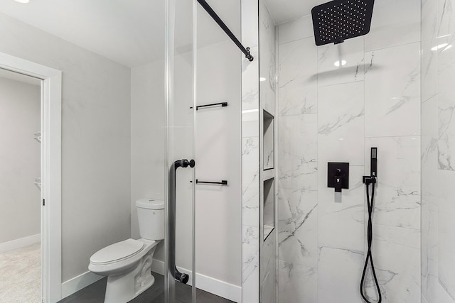 bathroom with toilet, baseboards, and a marble finish shower