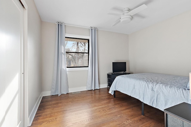 bedroom featuring visible vents, a ceiling fan, baseboards, and wood finished floors