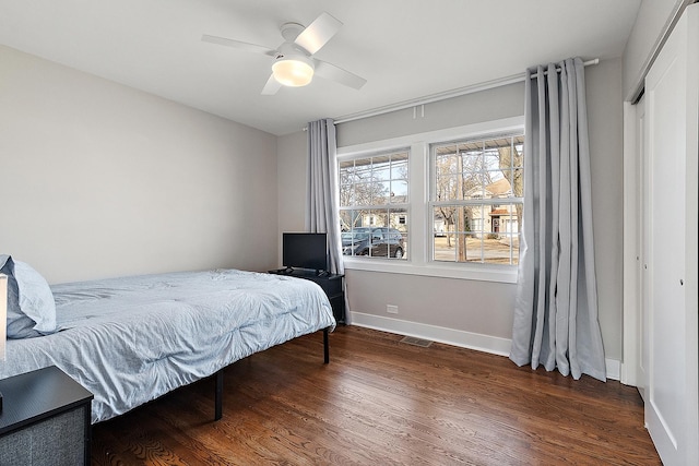 bedroom with visible vents, baseboards, wood finished floors, and a ceiling fan