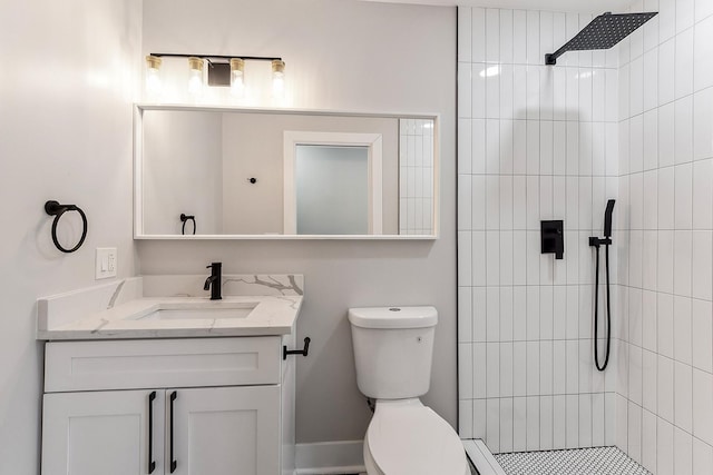 bathroom with vanity, toilet, and a tile shower