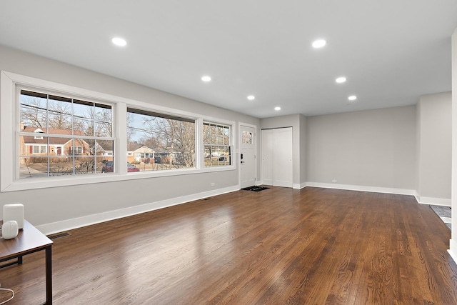 unfurnished living room featuring recessed lighting, dark wood-type flooring, and baseboards