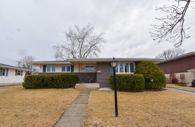 view of front of property featuring brick siding, a porch, and a front yard