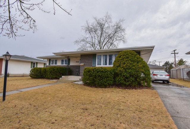 view of front of property featuring driveway, a front lawn, and brick siding