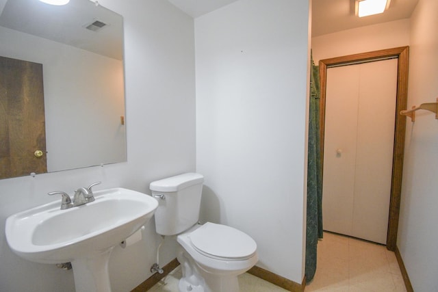 bathroom featuring toilet, baseboards, visible vents, and a sink