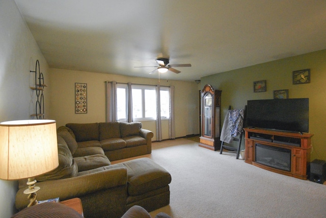 carpeted living area with a ceiling fan and a glass covered fireplace