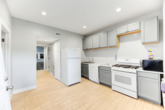 kitchen with gray cabinetry, white appliances, a sink, visible vents, and light countertops