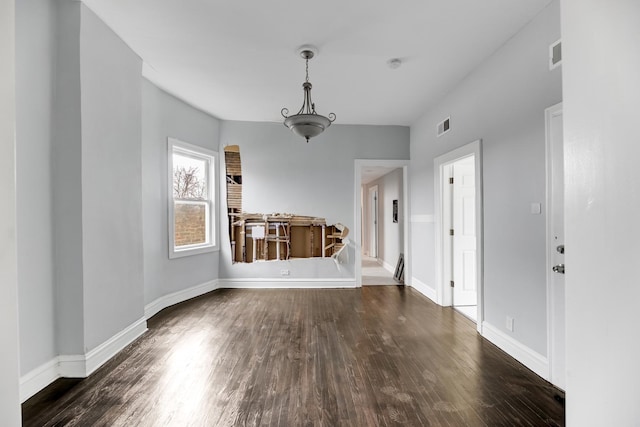 unfurnished dining area featuring baseboards, visible vents, and dark wood-type flooring