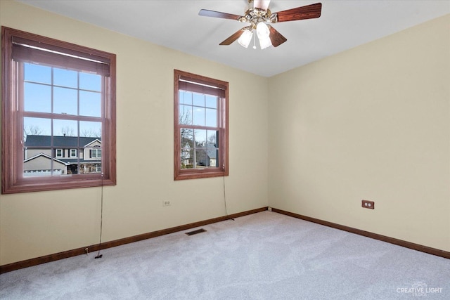 carpeted spare room with visible vents, ceiling fan, and baseboards