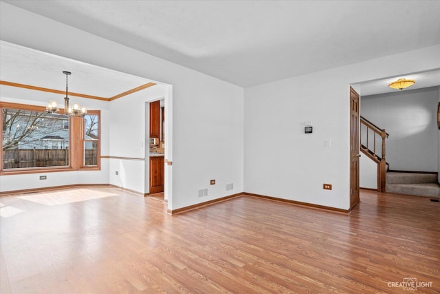 empty room with stairs, an inviting chandelier, baseboards, and light wood-type flooring