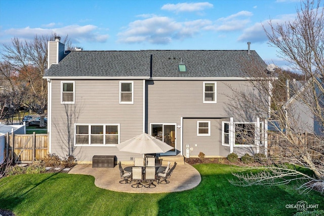 rear view of property with a lawn, a chimney, a patio, and fence