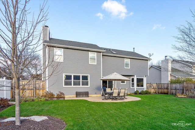 rear view of property featuring a yard, a patio, a chimney, and fence