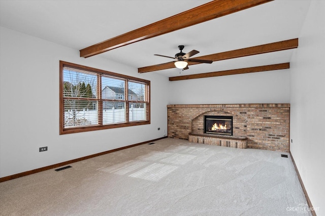 unfurnished living room with visible vents, a brick fireplace, baseboards, beam ceiling, and carpet flooring