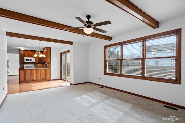 unfurnished living room featuring baseboards, visible vents, beam ceiling, light carpet, and ceiling fan with notable chandelier