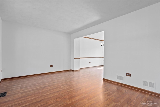 empty room with visible vents, baseboards, and wood finished floors