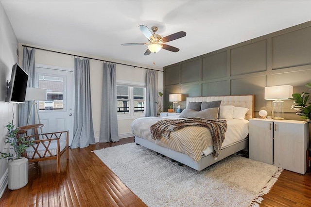 bedroom featuring hardwood / wood-style flooring, a decorative wall, and a ceiling fan