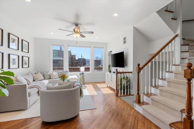 living area featuring ceiling fan, recessed lighting, wood finished floors, visible vents, and stairs